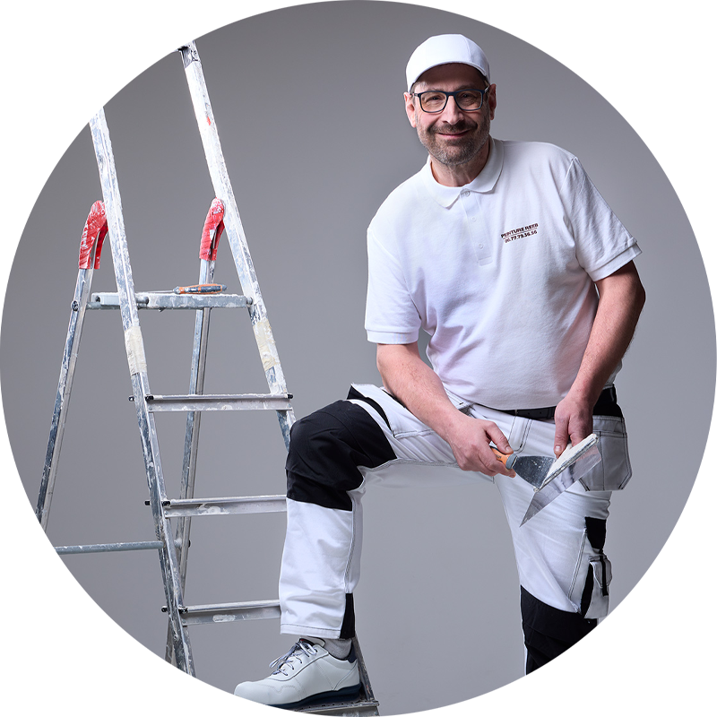 Photo d’André Reeb, artisan peintre à Mulhouse, préparant un chantier avec un escabeau, un seau de peinture et un couteau à enduire