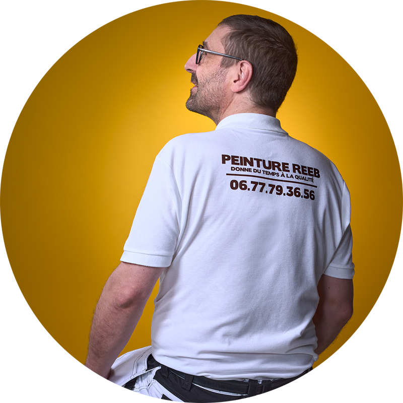 André Reeb – Artisan peintre à Mulhouse, Peinture Reeb Vue de dos d’André Reeb, artisan peintre à Mulhouse, portant un polo avec le logo et le numéro de Peinture Reeb