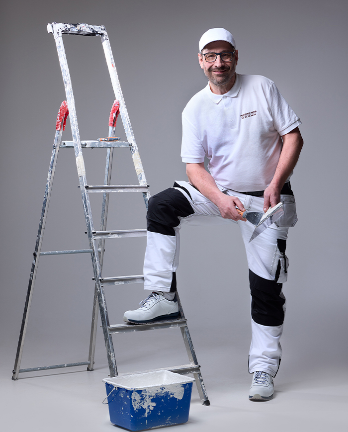 André Reeb – Artisan peintre à Mulhouse en pleine préparation de chantier Photo d’André Reeb, artisan peintre à Mulhouse, préparant un chantier avec un escabeau, un seau de peinture et un couteau à enduire